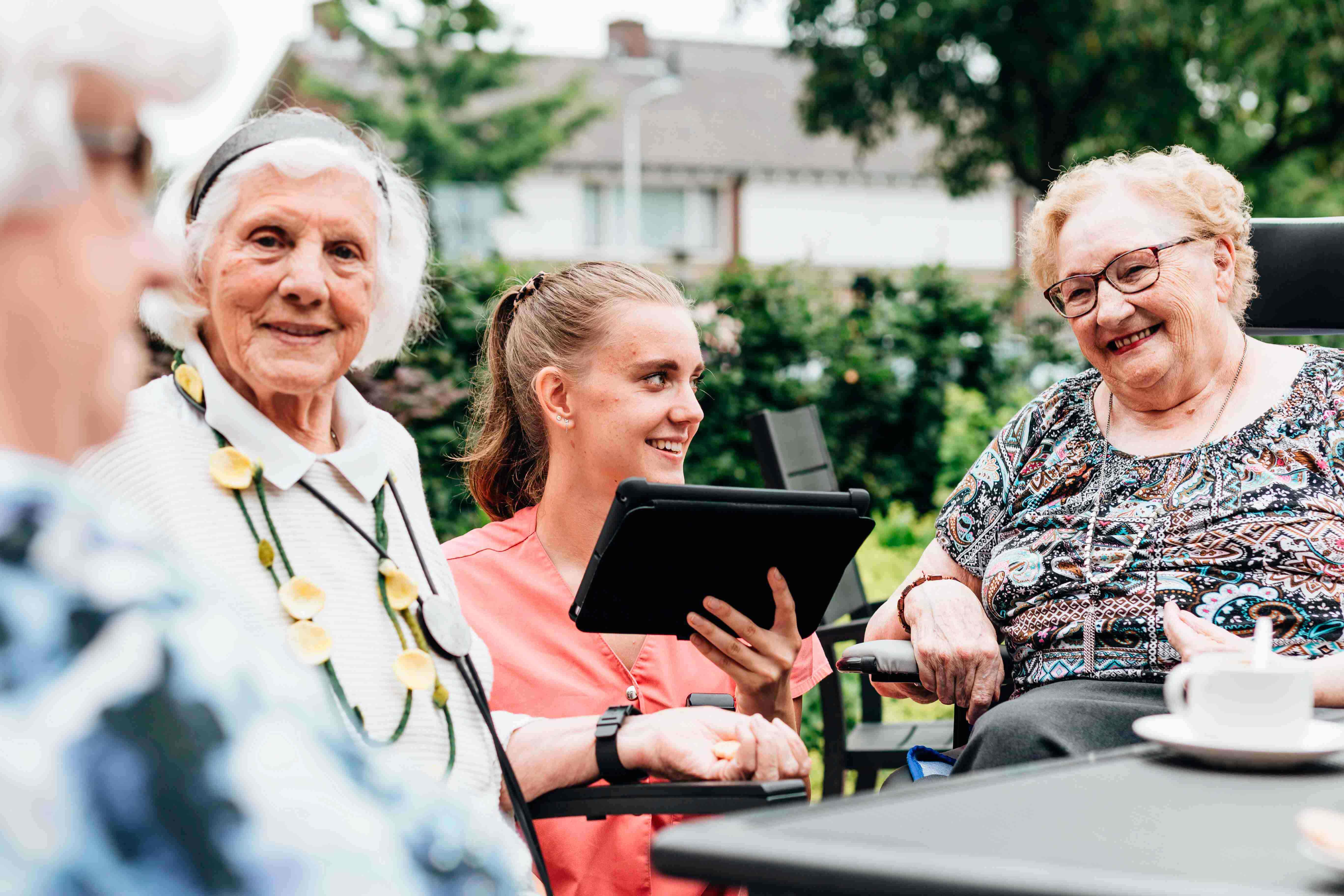 Zorgmedewerker met vrolijke cliënten in de vvt